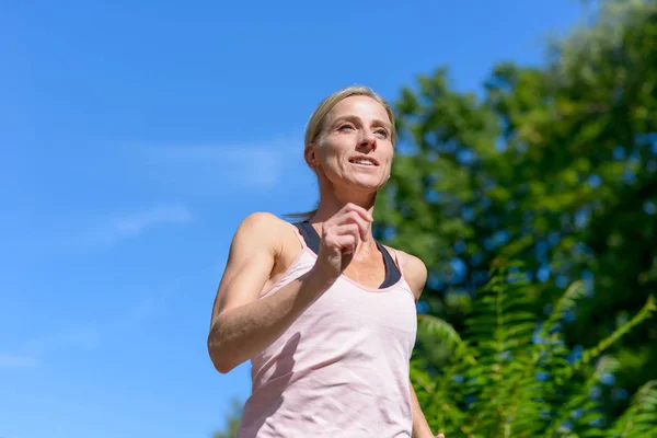 Retrato de una mujer sonriendo mientras corre al aire libre — Foto de Stock