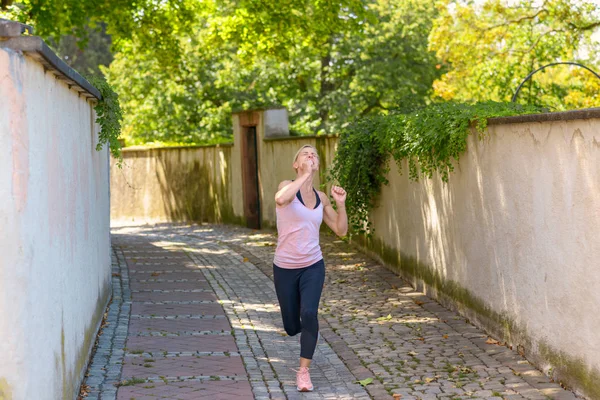 Ajuste mujer corriendo bajo frondosos árboles verdes — Foto de Stock