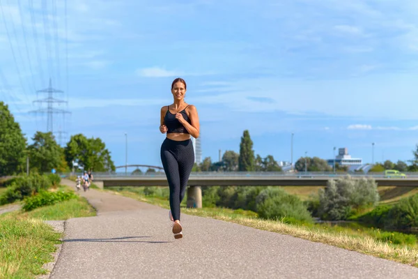 Fit mujer sana trotando junto a un río — Foto de Stock