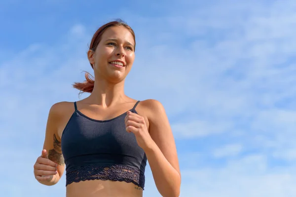 Smiling happy woman jogging outdoors in summer