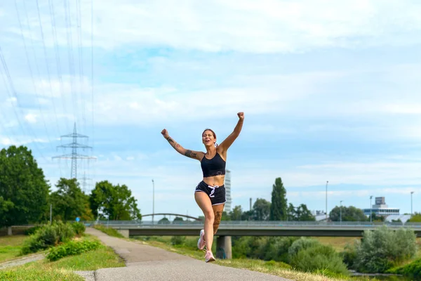 Mujer exuberante saltando en el aire mientras corre — Foto de Stock