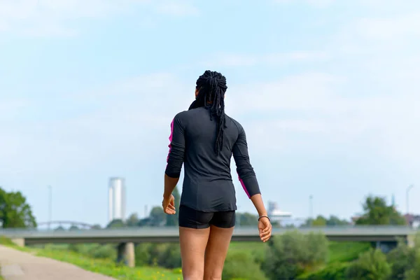 Deportiva mujer africana en forma trotando en un camino rural — Foto de Stock