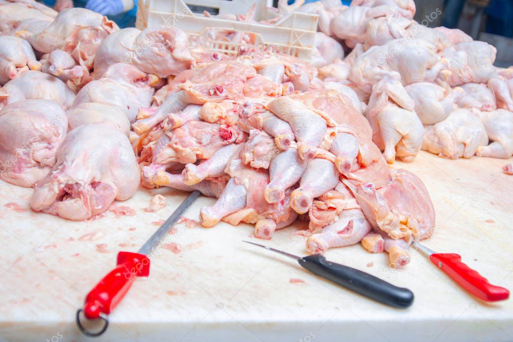 Chicken. Cutting shop of a poultry farm. Butcher is chopping a chicken.