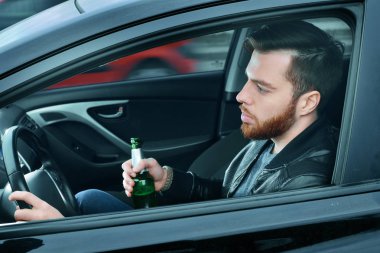 Elinde bir şişe alkolle araba süren sarhoş bir adam. Elinde direksiyon ve bira şişesi olan bir adam..