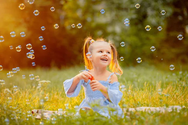 Una Niña Pequeña Sopla Burbujas Jabón Césped Verde Los Rayos — Foto de Stock