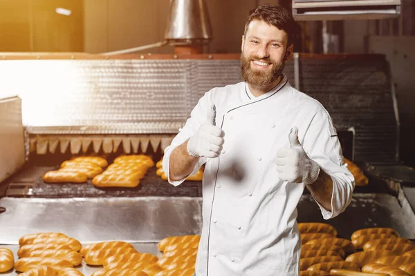 Portrait of a young baker on the background of an industrial oven in a bakery. Industrial bread production