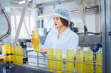 Çiçek ve zeytinyağı üretimi için fabrikada beyaz tulumlu genç ve güzel bir kız. Üretimde kalite kontrolü.