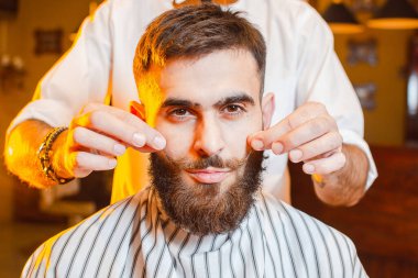 Berber, bir erkek berber dükkanında genç ve yakışıklı bir adam için güzel bir bıyık yapıyor. Berber Dükkanı.