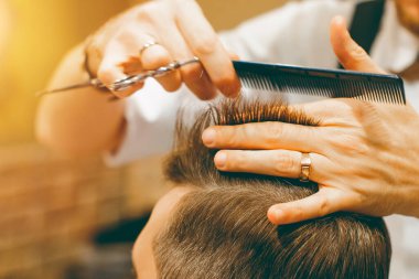 Berber saçlarını makasla kesiyor. Saç kesimi yakın plan. Berber dükkanı.