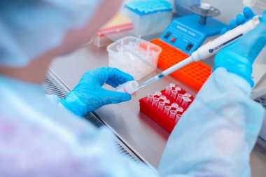 Laboratuvarda DNA testi. Elinde şeker kutusuyla laboratuvar teknisyeni steril bir laboratuvarda cam arkasında DNA analizi yapıyor..