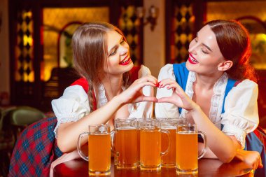 Ulusal kostümlü genç kızlar, Ekim Festivali 'nde ellerini bira bardaklarının üzerine koyup kalp yaptılar..