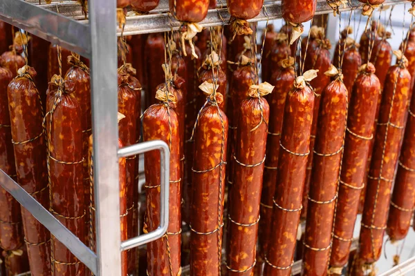 Tütsülenmiş sosis, tütsüleme evindeki metal bir çerçevede ipe asılmış..