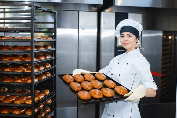 Young Girl Baker Holds Baking Tray Hot Pastries Background Industrial — Stock Photo, Image