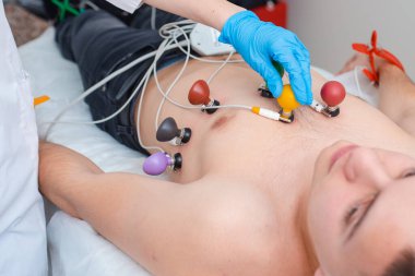 Kalp kardiyogramı. Doktor hastanın göğsüne elektrotlar takar. Kardiyoloji