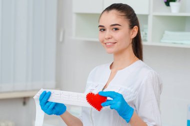 Kalbin kardiyogramı. Elinde kardiyogram kâğıt bant ve elinde kırmızı bir kalp olan bir doktor. Elektrokardiyograf değerleri