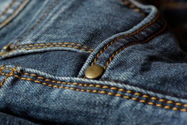 Mavi jeans turuncu dikiş ile bir parça Close-up. Perçin yakın çekim ile cep.