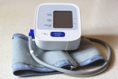Ahşap bir masa beyaz elektronik tonometer yakın çekim. Kan basıncı ölçümü. Sağlıklı kavramı.
