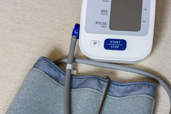 Ahşap bir masa beyaz elektronik tonometer yakın çekim. Kan basıncı ölçümü. Sağlıklı kavramı.