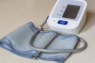 Ahşap bir masa beyaz elektronik tonometer yakın çekim. Kan basıncı ölçümü. Sağlıklı kavramı.