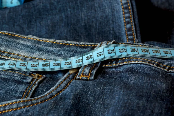 蓝色牛仔裤和一条蓝色的卷尺特写 尺寸测量 饮食和健康 — 图库照片