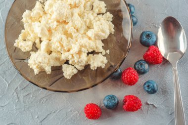 Taze ahududu ve yaban mersini olgun çilek ile sağlıklı bir kahvaltı için bir tabak içinde süzme peynir. Doğal sağlıklı bir ürün.