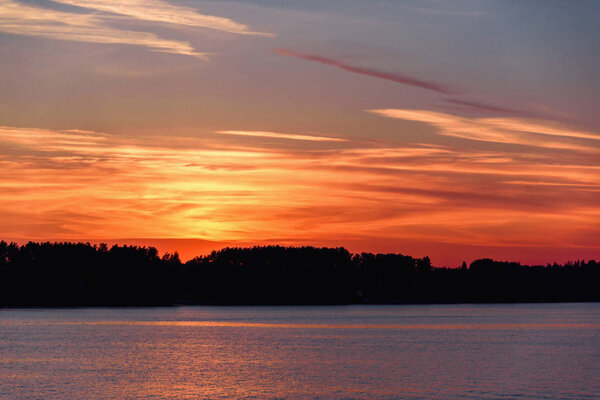 Яркий, красочный и драматичный закат на реке. Вечером солнце прячется за деревьями. Блеск заходящего солнца на воде
.