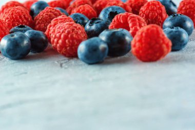 Yaban mersini ve ahududu gri çimento arka plan üzerinde karıştırın. Olgun ve sulu taze ahududu ve yaban mersini yakın çekim. Bir sürü çilek yakın çekim.