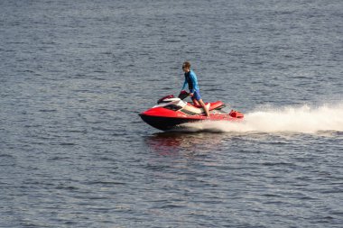 Bir adam nehirde kırmızı bir jet ski ye biniyor. Rusya, Moskova bölgesi, Ağustos 2108.