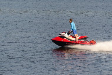 Bir adam nehirde kırmızı bir jet ski ye biniyor. Rusya, Moskova bölgesi, Ağustos 2108.