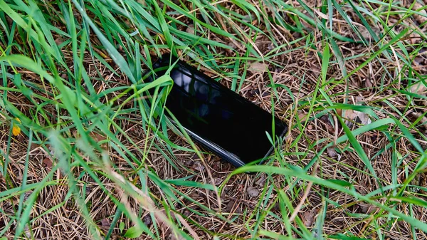 Kayıp bir cep telefonu çim yakın çekim yatıyor. Telefon kaybı.