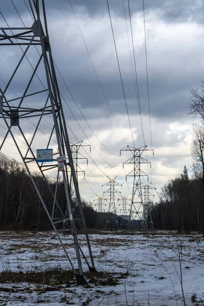 High-voltage power lines on a winter evening. Power distribution line. Clearing in the forest under the power line.