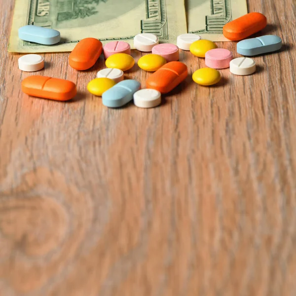 Masada çeşitli renkli haplar ve para var. Hap alma kavramı. Tabletlerin fiyatını arttırma kavramı.