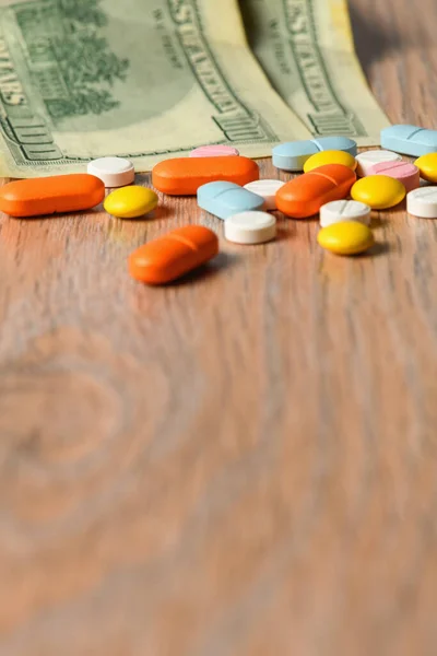 Assorted colored pills and money on the table. The concept of buying pills. The concept of increasing the price of tablets.