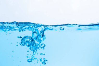 Mavi su dalgalarının yüzeyi beyaz bir zemine vuruyor.