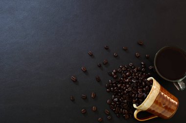 Kahve çekirdekleri ve kahve fincanları masanın üstünde oturuyor.
