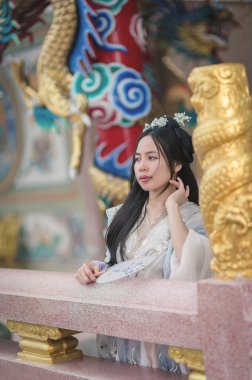 A young woman elegantly poses in a beautiful Hanfu, showcasing traditional Chinese attire. Her serene expression and surroundings highlight cultural heritage and artistic craftsmanship.