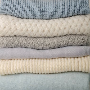 Örme giyim (kazak, eşarplar, pullovers) mavi, beyaz ve gri renkler yığını. Seçici odak.