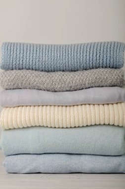 Örme giyim (kazak, eşarplar, pullovers) mavi, beyaz ve gri renkler yığını. Seçici odak.