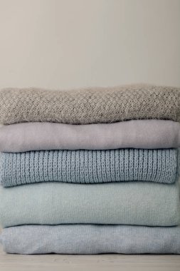 Örme giyim (kazak, eşarplar, pullovers) mavi, beyaz ve gri renkler yığını. Seçici odak.