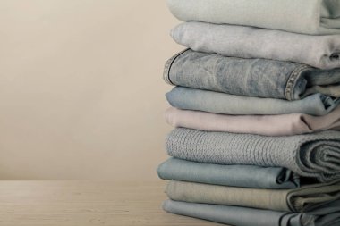 Kot pantolon ve örme giyim (kazak, eşarplar, pullovers) mavi, beyaz ve gri renkler yığını. Seçici odak.