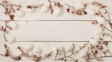 Mutlu Paskalyalar. Paskalya dekorasyon - Paskalya yumurtaları ve çiçekli dallar Beyaz ahşap zemin üzerinde. Seçici odak.