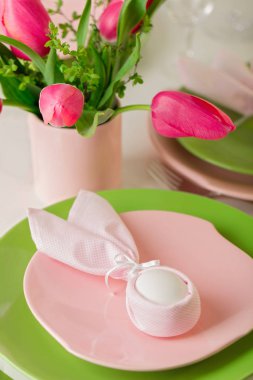 Mutlu Paskalyalar. Dekor ve Paskalya tablonun tablo ayarını pembe laleler ve yemekleri pembe ve yeşil renk ile bir vazo var. Seçici odak.