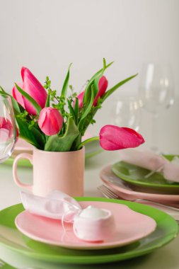 Mutlu Paskalyalar. Dekor ve Paskalya tablonun tablo ayarını pembe laleler ve yemekleri pembe ve yeşil renk ile bir vazo var. Seçici odak.