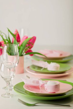 Mutlu Paskalyalar. Dekor ve Paskalya tablonun tablo ayarını pembe laleler ve yemekleri pembe ve yeşil renk ile bir vazo var. Seçici odak.