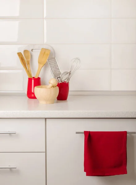 Interior white kitchen with kitchen tools and red crockery. Selective focus.