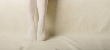 Beyaz bir arka plan üzerinde sıcak beyaz örme taytlı kadın bacakları faux kürk ürünleri