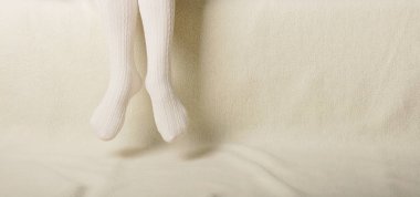 Beyaz bir arka plan üzerinde sıcak beyaz örme taytlı kadın bacakları faux kürk ürünleri.