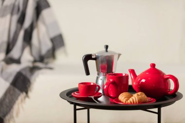 Yuvarlak siyah metal sehpa ile kahve makinesi ve bir su ısıtıcısı arka planı gri bir battaniye ile beyaz bir kanepe ve çay için. Seçici odak.