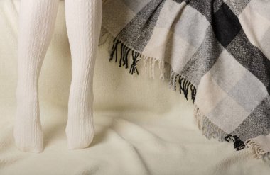 Beyaz bir arka plan üzerinde sıcak beyaz örme taytlı kadın bacakları faux kürk ürünleri.