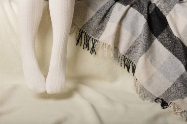 Beyaz bir arka plan üzerinde sıcak beyaz örme taytlı kadın bacakları faux kürk ürünleri.